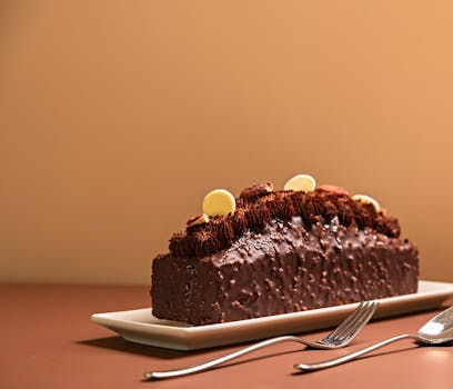 Gâteau praliné noisette sur un plat, décoré de crème chocolat et de petits biscuits, sur fond beige.