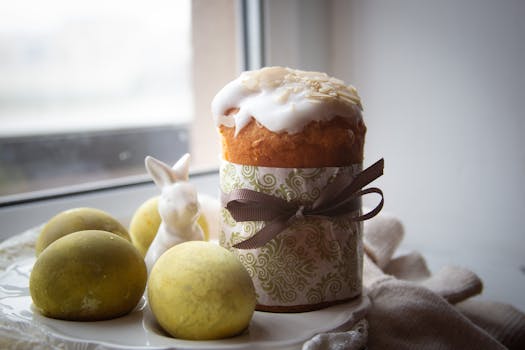 Gâteau décoré avec glaçage et œufs en chocolat sur une assiette près d'une fenêtre.